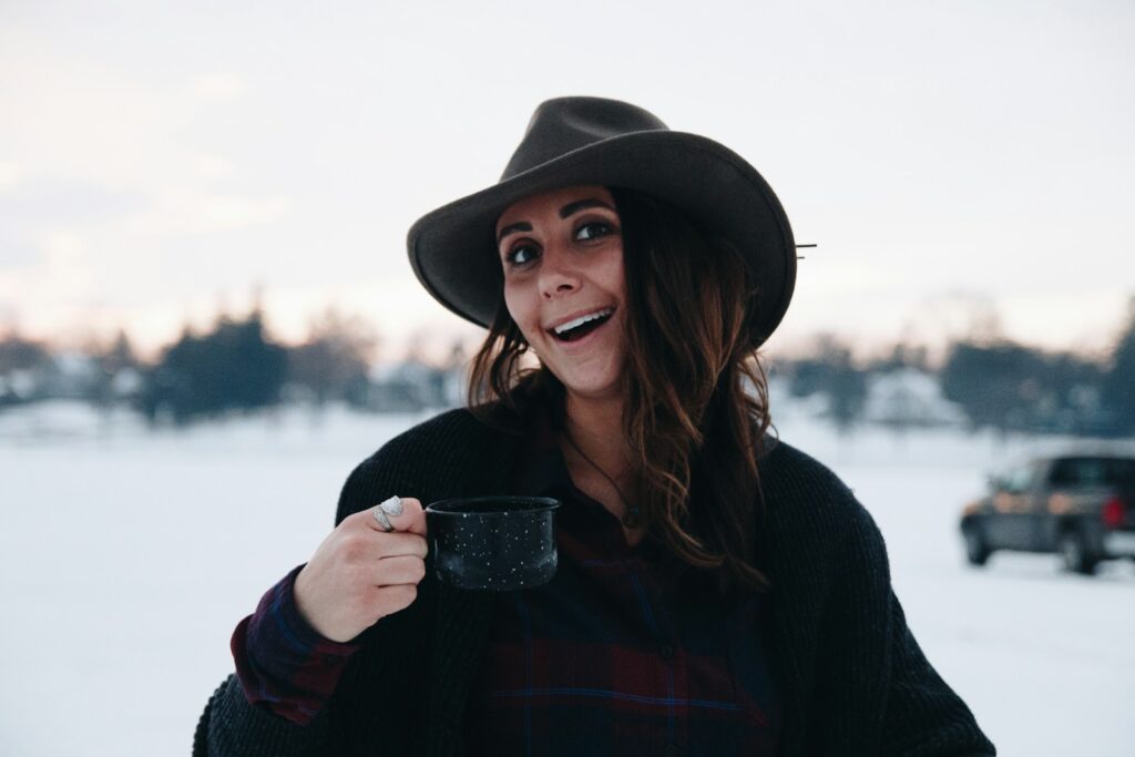 A woman wearing a hat and holding a cup